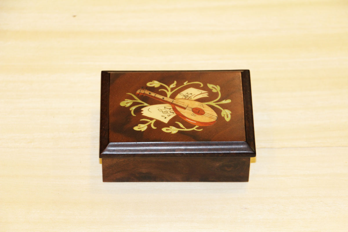 Scatola in legno intarsiato adornata di strumenti musicali